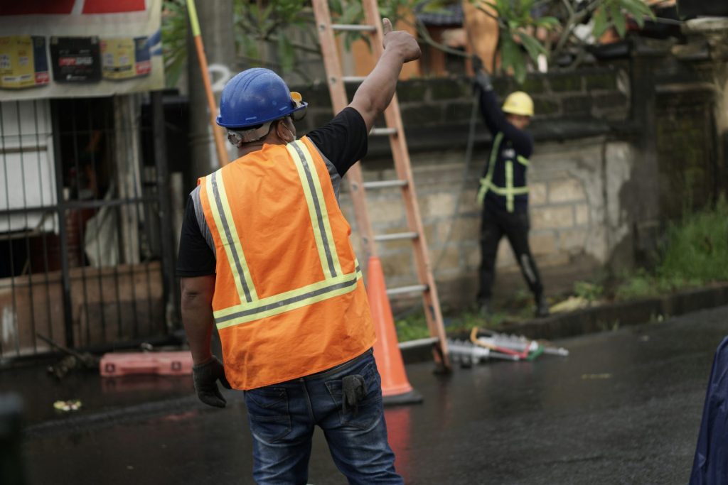 un homme portant un gilet de sécurité orange et une échelle